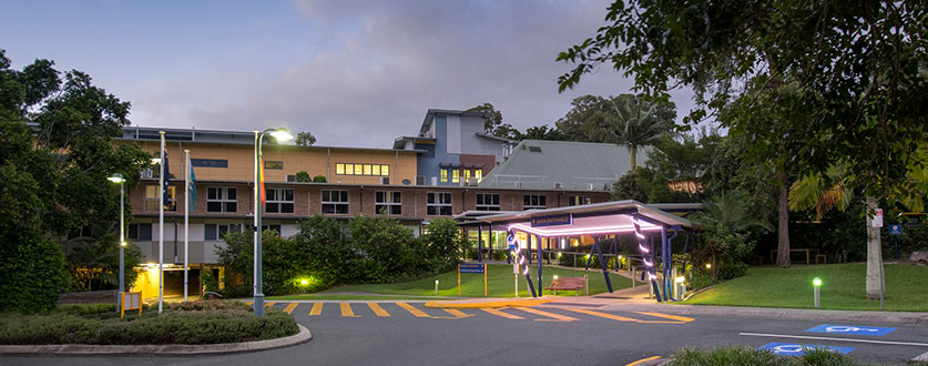 An exterior view across the car park to Buderim Private Hospital buildings at dusk.