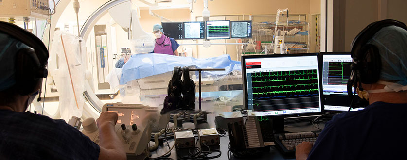 Two medical professionals monitor screens as a surgeon operates in the cardiovascular theatre at Buderim Private Hospital.